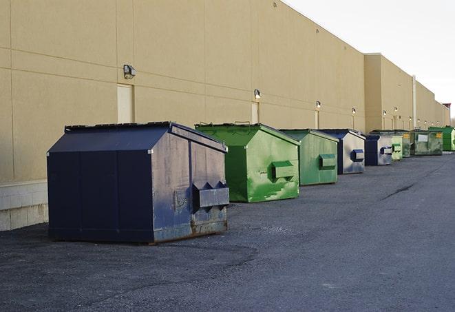 a pile of demolition waste sits beside a dumpster in a parking lot in Berino